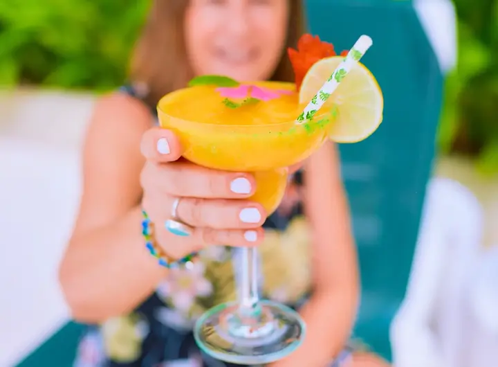 Person holding fresh tropical mango cocktail